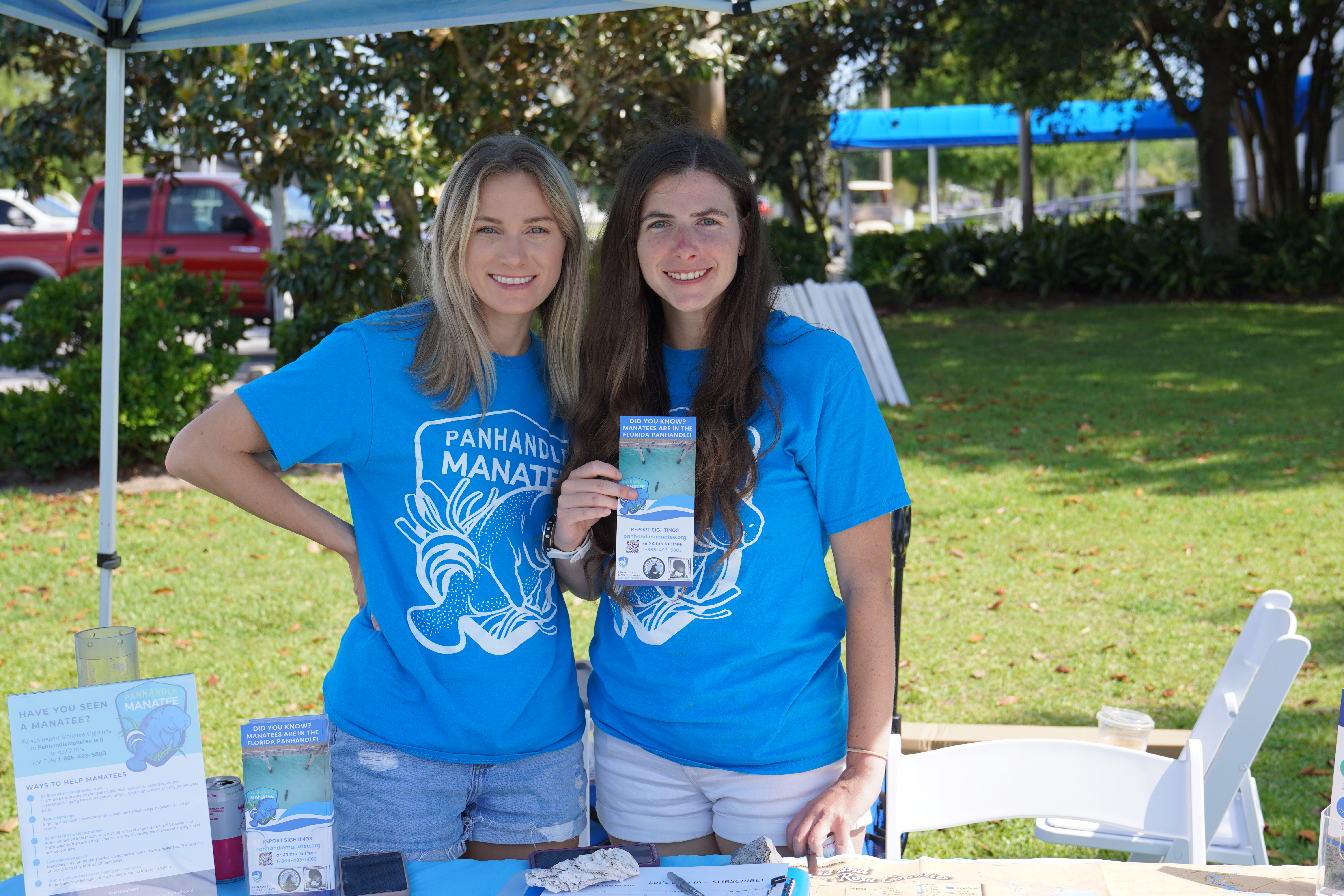 Two people holding manatee outreach materials at a table