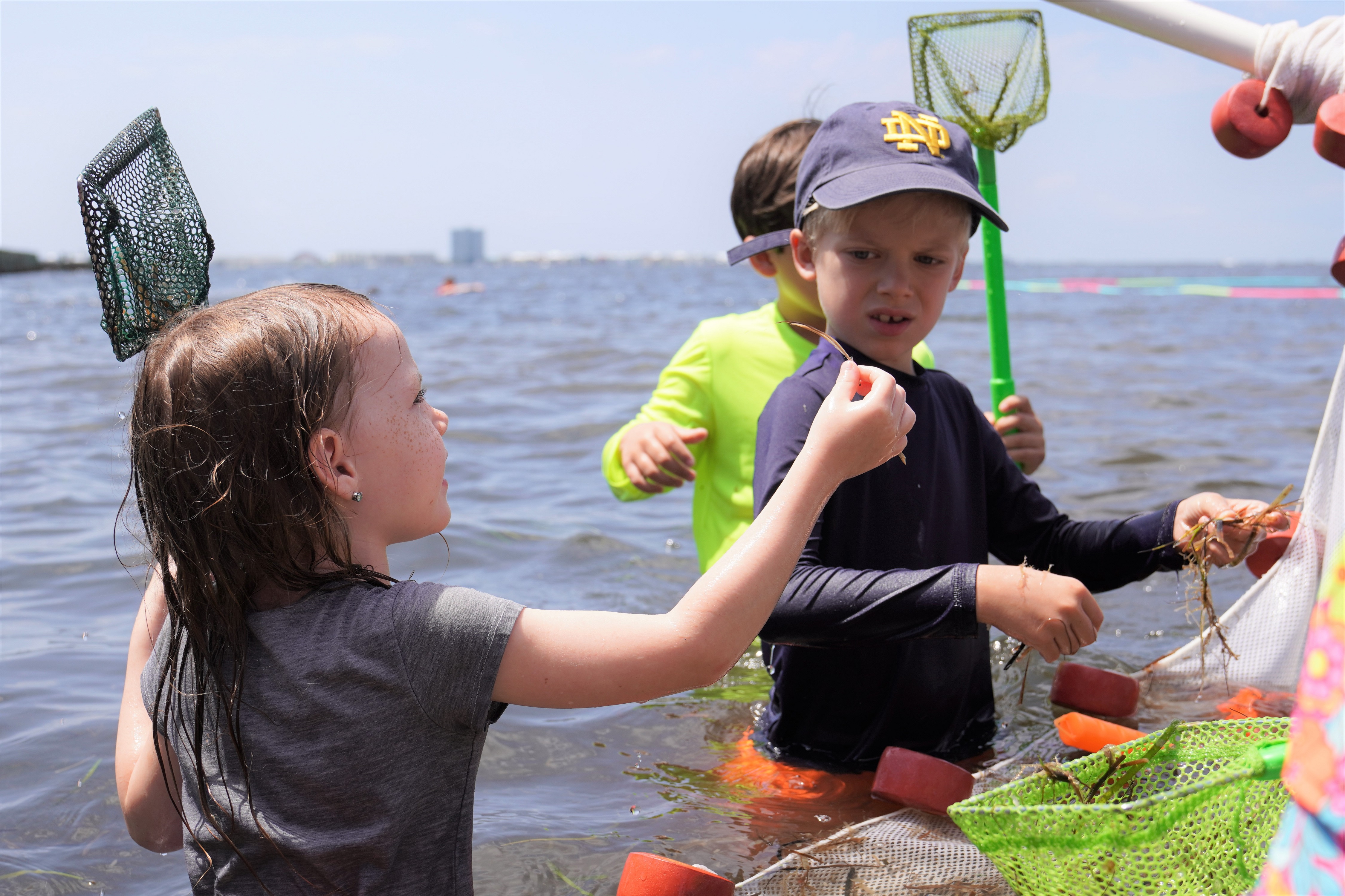 Two kids holding small nets in water